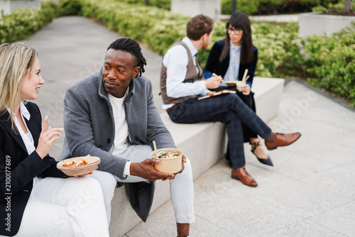 Multiracial business people doing lunch break outside during fall time - Outdoor meeting and entrepreneur concept - Focus on african man face
