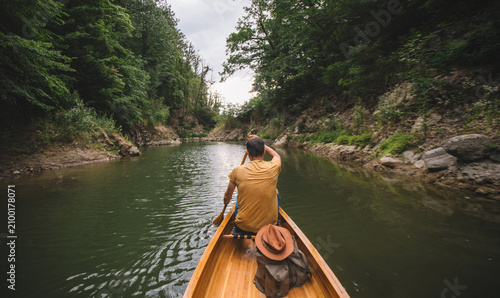 Rear view of man paddling canoe on forest lake