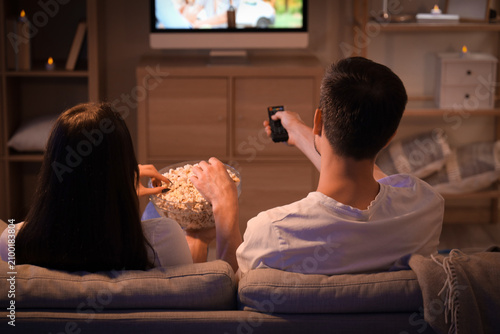 Couple with popcorn watching TV at home in evening