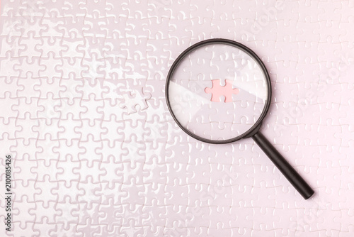 Magnifying Glass searching missing puzzle piece on background. Search solution, problem solving, investigation, business analysis, finding answers, research, discovery, attention to detail, strategy a