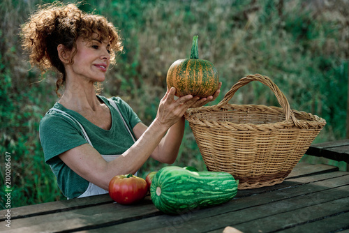 Obraz na płótnie Woman holding a freshly harvested organic pumpkin from her sustainable urban garden