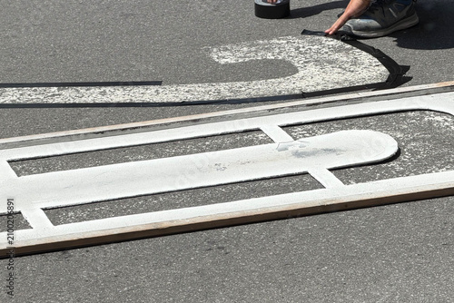 Road worker painting speed limit 20 marking on asphalt street