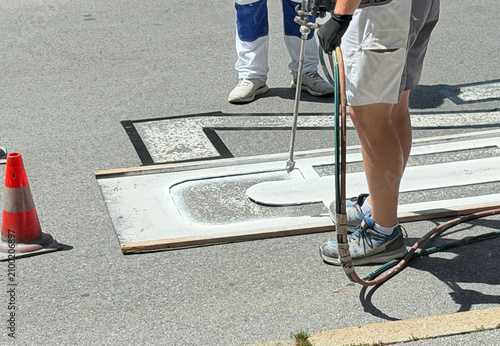 Road worker painting speed limit 20 marking on asphalt street