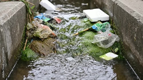 Polluted Water Flowing Through Drainage System Filled With Plastic Waste And Green Algae, Highlighting Environmental Issues And Pollution Awareness