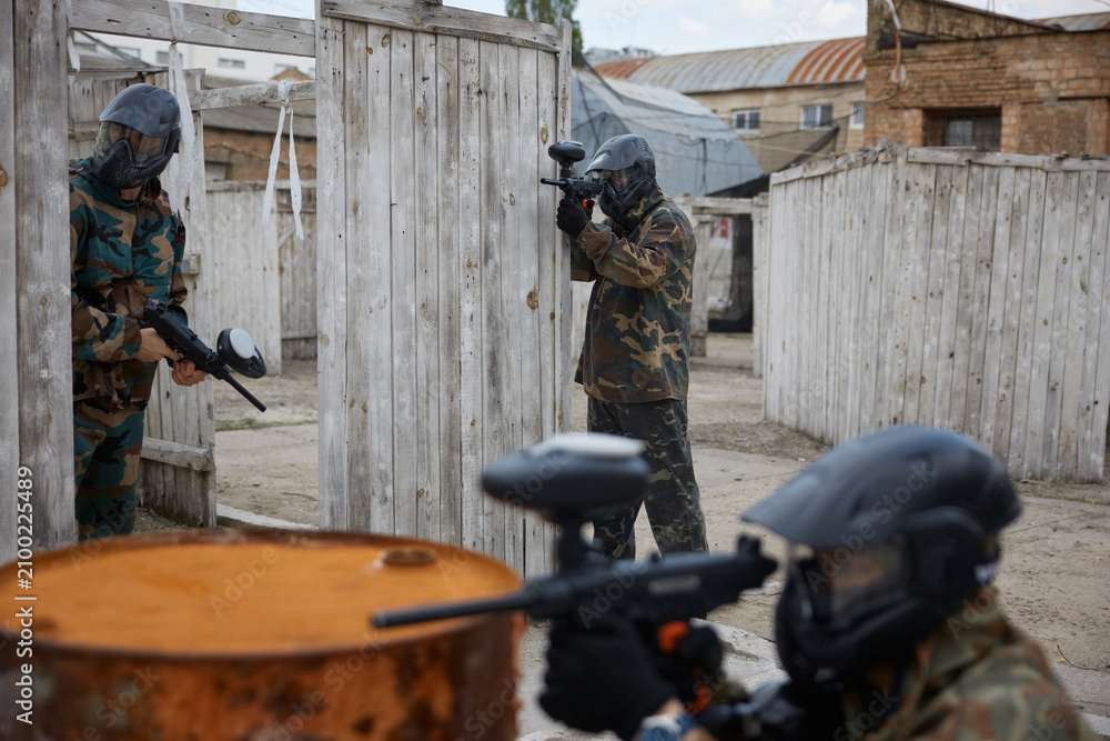 Fototapeta premium An armed group of several soldiers practice with weapons on training field with artificial barriers