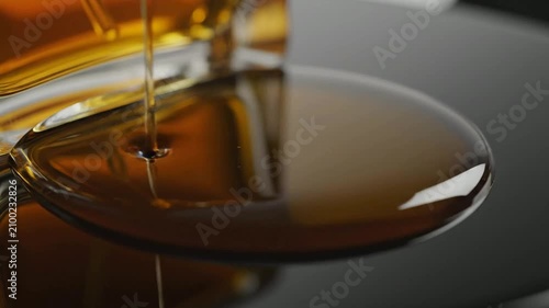 Viscous Amber Liquid Elegantly Pouring Onto Glossy Black Surface In Close-Up Macro Photography Perfect For Beauty And Cosmetic Visuals
