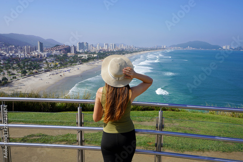 Beautiful young tourist woman enjoying cityscape from belvedere in Guaruja, Sao Paulo, Brazil