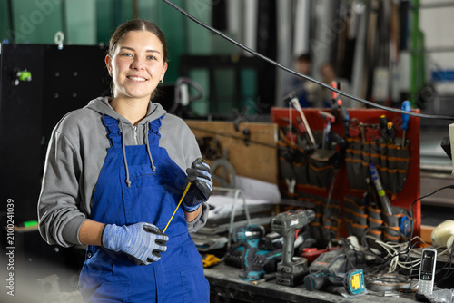 фотографія Girl glazer employee in blue overall works in glass processing shop