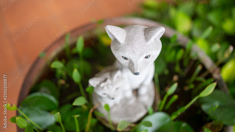 Fototapeta premium Decorative fox statue with greenery in a garden