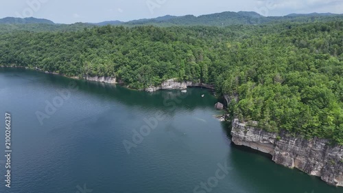 Aerial drone overflight capturing the steep rocky cliffs and deep river valley inside New River Gorge National Park, West Virginia. Dense green summer forest wilderness scenery.