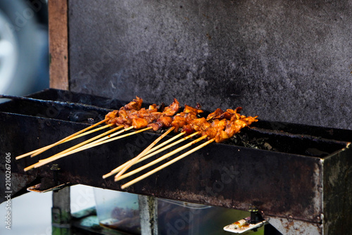 Foto Chicken satay with charcoal ingredient on red fire grilling by people