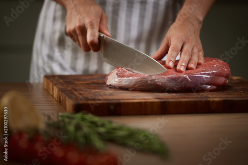 Chef hands slicing raw beef steak for cooking