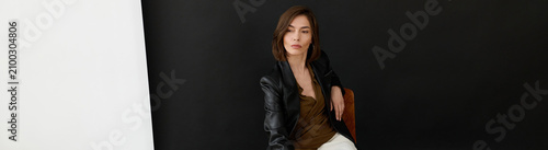 Fotografie A stylish woman with a bob haircut sits on a chair in a bright room, banner