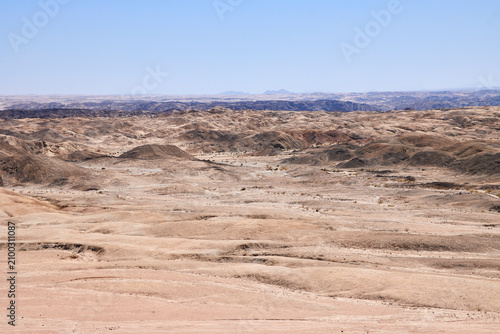 Foto Karge Wüstenebene mit sanften Hügeln und wenig Vegetation bei Swakopmund in Namibia