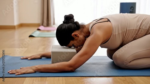 Woman Practicing Yoga Child's Pose With Block in Serene Indoor Studio Setting for Enhanced Relaxation and Mindfulness