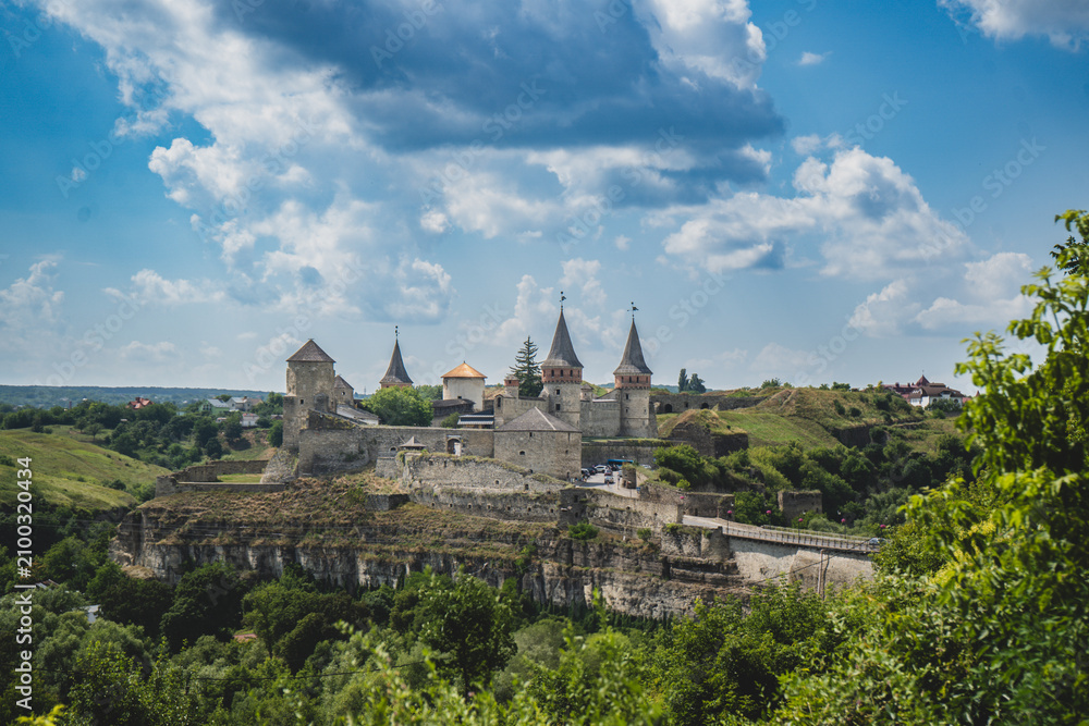 Obraz premium Ancient stone fortress perched on a cliff overlooking a lush green valley