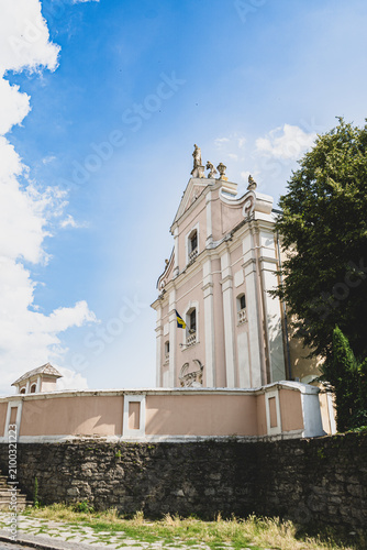 Baroque church facade with Ukrainian flag under a bright blue sky