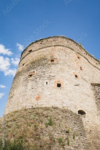 Ancient stone fortress tower against a bright blue sky with scattered clouds