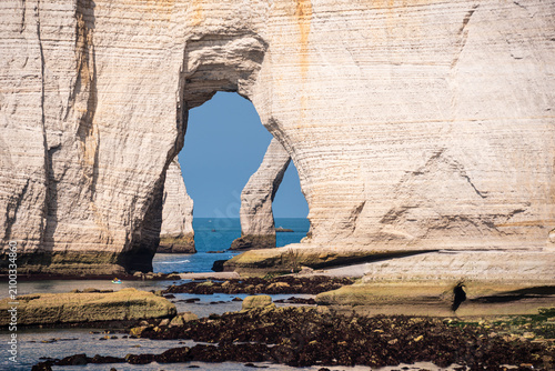 Natural arch formation at Etretat overlooking the English Channel in Normandy, France with clear blue sky and rocky shoreline