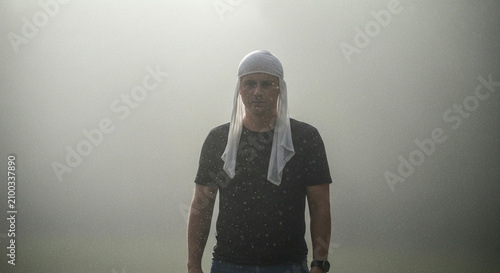 Mysterious Man Standing in Thick White Fog Wearing a White Head Wrap and Dark T-shirt
