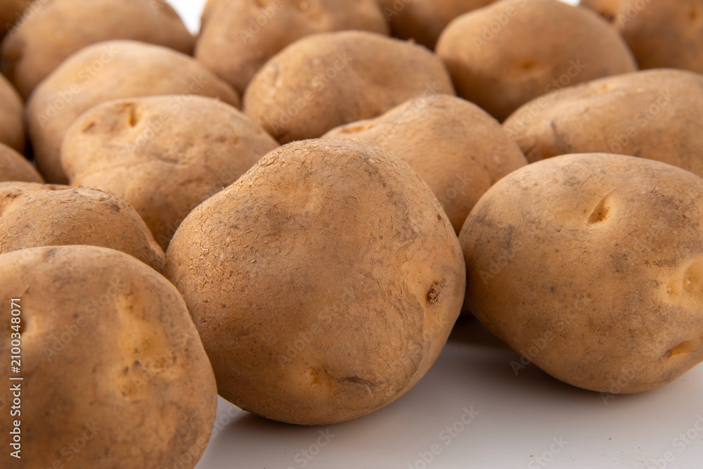 Fototapeta premium Freshly harvested potatoes with soil on white background, closeup food stock photo