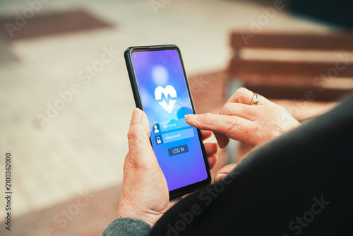 Senior woman logging into health monitoring app on smartphone. Health apps, medical technology, and elderly healthcare management concepts.
