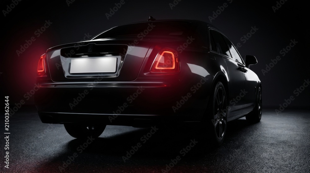 Naklejka premium Luxury black sedan with glowing red taillights at night. High-end car showcasing sleek rear design and premium automotive lighting.