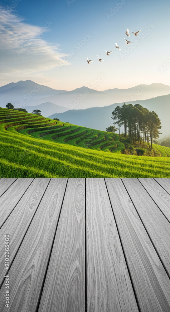 Obraz premium Verdant rice terraces ascend hills with misty mountains beyond, graced by flying doves. A wooden foreground offers a natural showcase, symbolizing harmony and peace.
