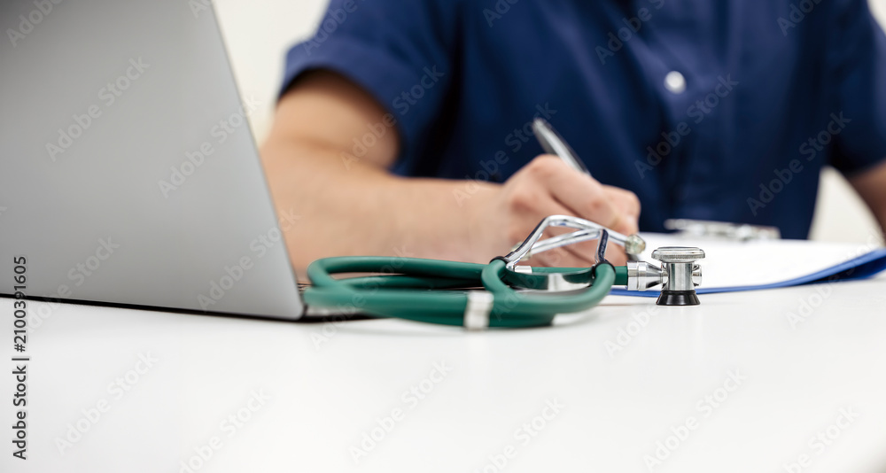 Fototapeta premium Medical professional taking notes in a patient chart at a modern clinic. Concept clinical documentation, healthcare, medical records, patient care, professional medicine.