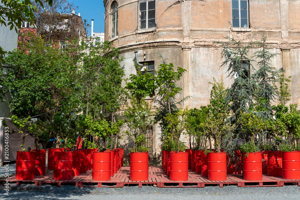 Obraz premium Plants grow in red containers near a historic building in a public space during daylight