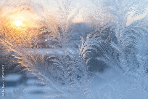 Foto Frosted windowpane with feather-like ice patterns in morning light