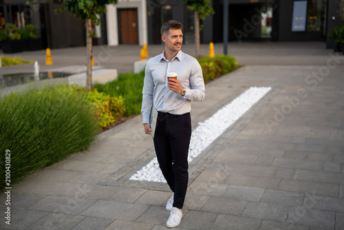 Successful businessman holding coffee walking during city commute