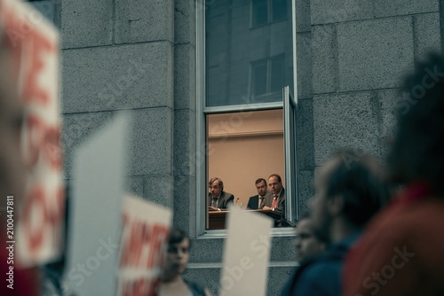 Civilian protesters gather outside a government building while lawmakers discuss inside