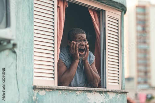 Man screams from apartment window in Santos city during the warm evening light