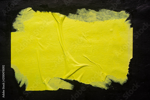 A yellow poster with folds on a black background, close-up