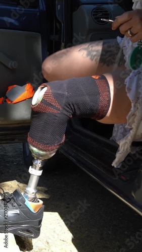 Independent woman with a prosthetic leg getting out of her car. Detail shot of her bionic limb as she exits the vehicle and locks the door