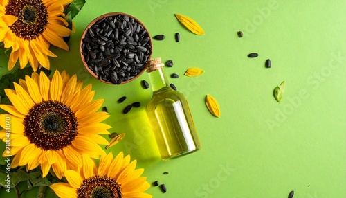 Top of view Oil bottle with sunflowers and seeds on a green background