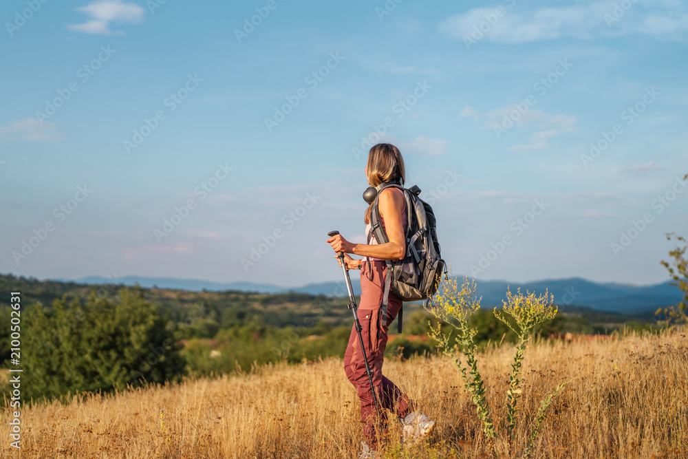 Fototapeta premium Woman hiking in nature observing mountain view at sunset