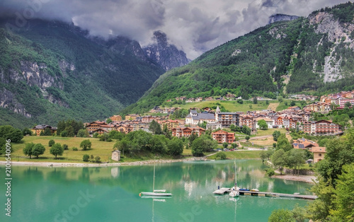 lake of Molveno in Brenta Dolomites in Italy with village at the edge of beautiful turquoise water mountains background under cloudy sky