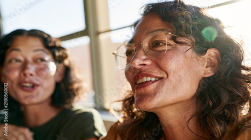 Two Women Sharing a Smile, Laughing Together in Bright Light, Modern Urban Setting