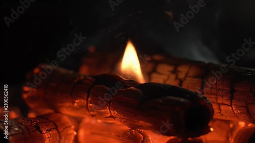 A close-up video of a burning incense stick glowing brightly within a decorative metal holder on a dark background