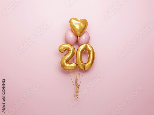Gold number 20 balloons with heart for birthday and anniversary celebration, flat lay on pink background