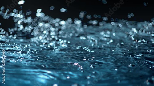 Fresh blue water macro background loop with splashing liquid on dark black backdrop. 3D animation wave fluid swirling backplate with copy space. Clean abstract bubbles texture.