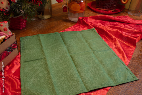 Table setting with green cloth and red fabric near holiday decorations and a drink