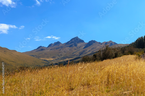 Panoramic view of the peaks of the extinct Pasochoa volcano from its eastern slopes in the Andes Mountains, Ecuador, under a clear blue sky during the