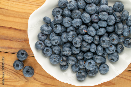Ripe blueberries on a ceramic plate, close-up, top view.