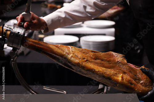 Tableau sur toile jamón ibérico en una tabla de corte de jamón con el experto cortador