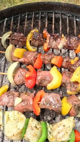 Flipping meat and fish skewers on a charcoal grill for even cooking.