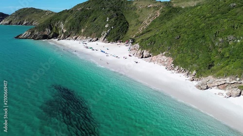Cinematic aerial drone side tracking footage of Pontal do Atalaia Beach in Arraial do Cabo, Rio de Janeiro, Brazil featuring crystal-clear turquoise waters, tropical coastline and pristine white sand