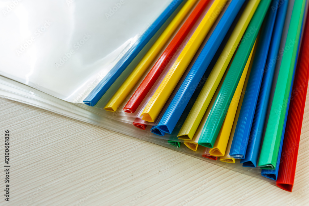 Fototapeta premium The ends of colored binder clips lie together on an office desk.